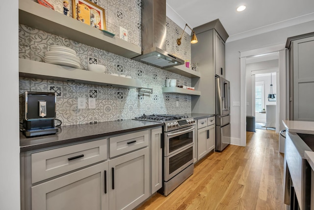 kitchen with wall chimney range hood, gray cabinetry, stainless steel appliances, and light wood-type flooring