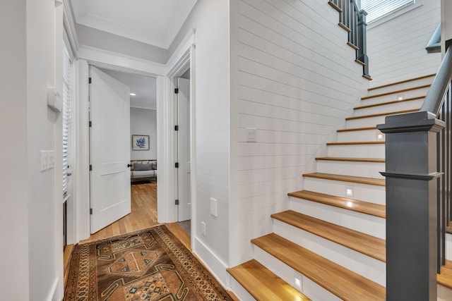 staircase with hardwood / wood-style floors and crown molding