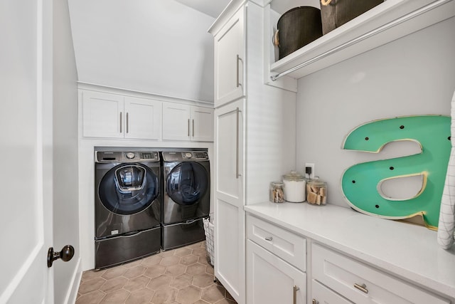 clothes washing area with cabinets and washing machine and dryer