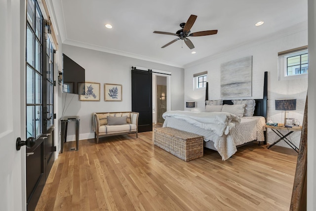 bedroom featuring multiple windows, light hardwood / wood-style flooring, ceiling fan, and a barn door