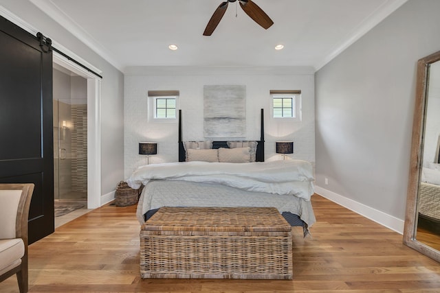 bedroom with crown molding, ceiling fan, a barn door, and light hardwood / wood-style floors