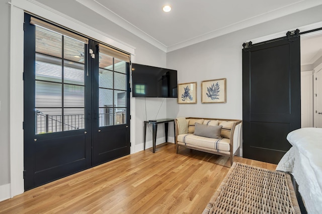 interior space with ornamental molding, french doors, a barn door, and light hardwood / wood-style floors