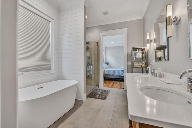 bathroom featuring plus walk in shower, tile patterned flooring, crown molding, and vanity