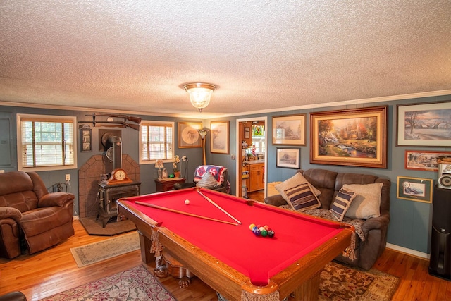 game room with billiards, a wood stove, hardwood / wood-style flooring, a textured ceiling, and crown molding