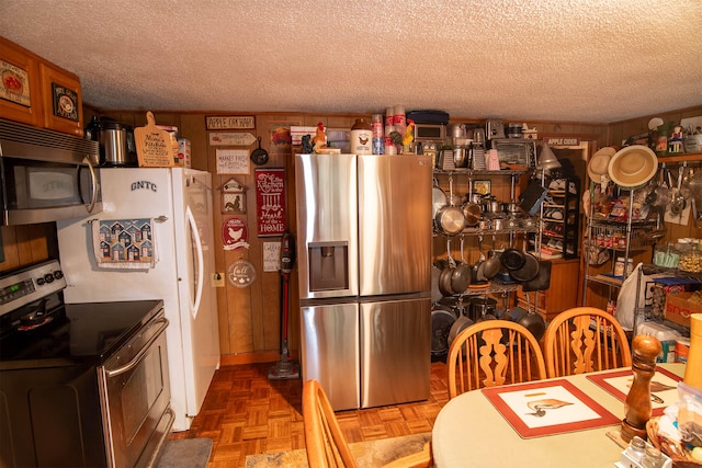 kitchen with parquet floors, stainless steel appliances, and a textured ceiling