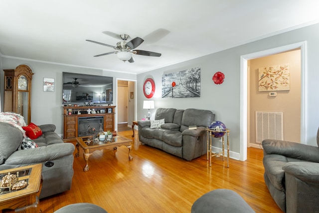 living room featuring ceiling fan, ornamental molding, and hardwood / wood-style floors