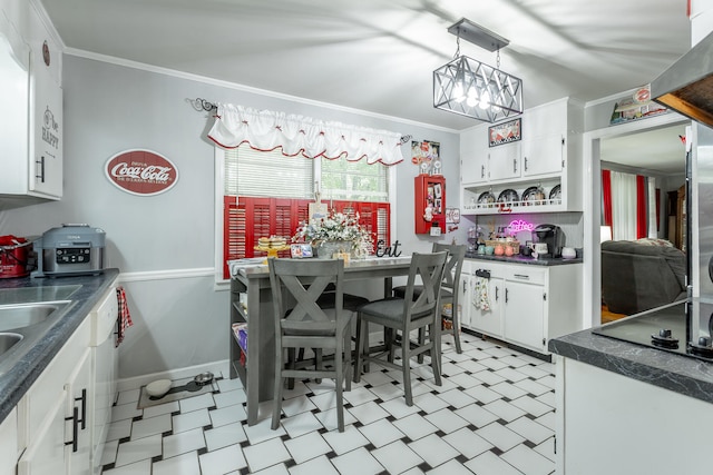 kitchen with black electric stovetop, ornamental molding, white cabinets, and a notable chandelier