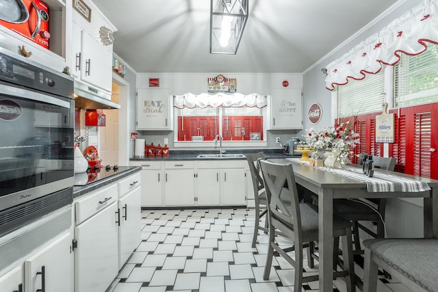 kitchen with white cabinetry, sink, black electric cooktop, stainless steel oven, and ornamental molding