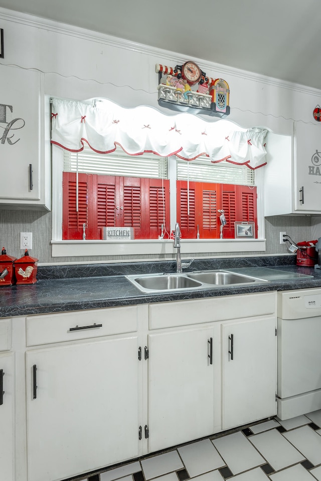 kitchen with white dishwasher, crown molding, white cabinetry, and sink