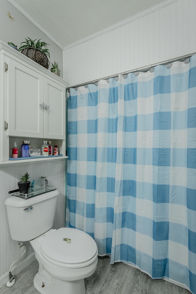 bathroom with crown molding, hardwood / wood-style floors, walk in shower, toilet, and a textured ceiling