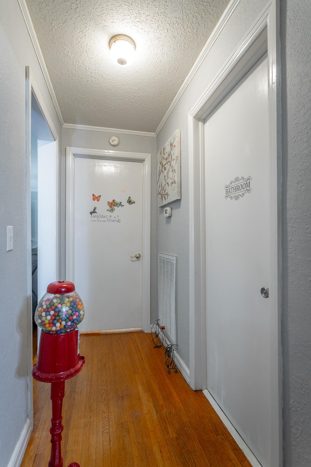 hallway with ornamental molding, a textured ceiling, and hardwood / wood-style floors