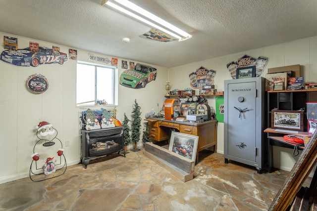 miscellaneous room with a wood stove and a textured ceiling