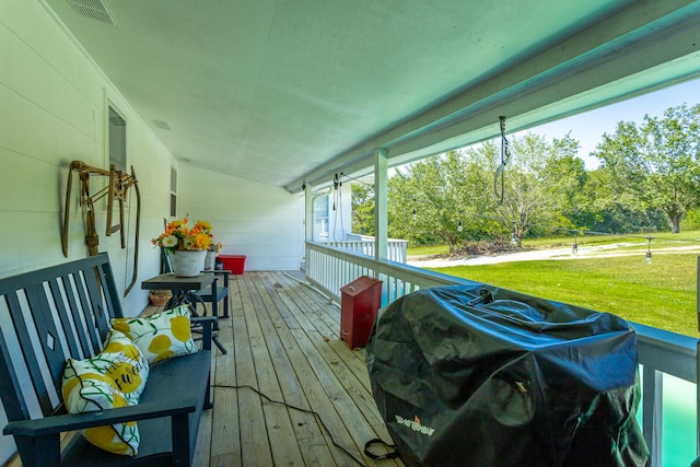 wooden terrace featuring a grill, a lawn, and a porch