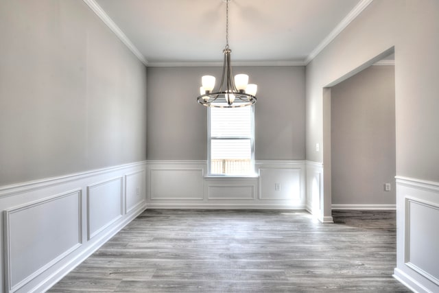 unfurnished dining area with light hardwood / wood-style flooring, ornamental molding, and a chandelier