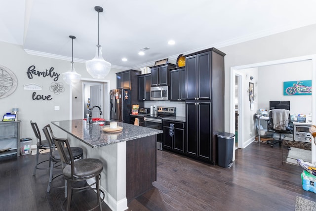 kitchen featuring hanging light fixtures, stainless steel appliances, dark hardwood / wood-style floors, a kitchen breakfast bar, and a center island with sink