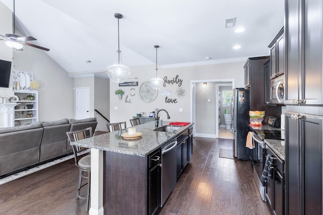 kitchen featuring stainless steel appliances, dark hardwood / wood-style flooring, light stone counters, an island with sink, and lofted ceiling