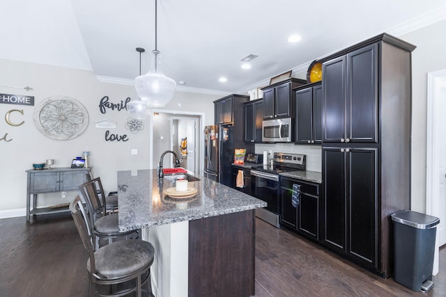 kitchen with a center island with sink, dark wood-type flooring, stainless steel appliances, sink, and stone counters