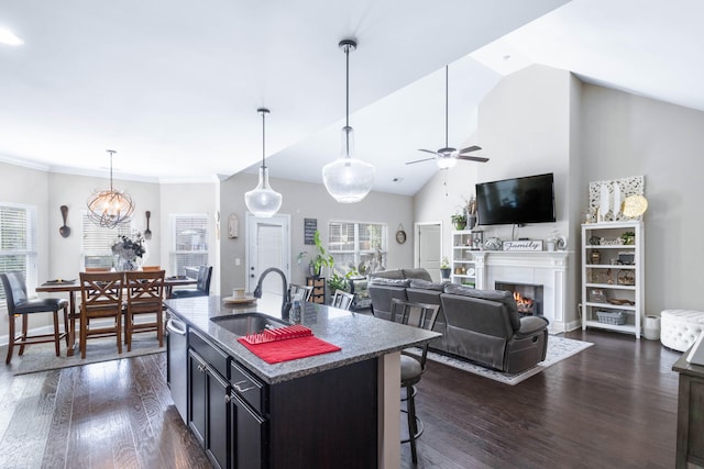 kitchen with dark hardwood / wood-style flooring, ceiling fan with notable chandelier, a center island with sink, and vaulted ceiling