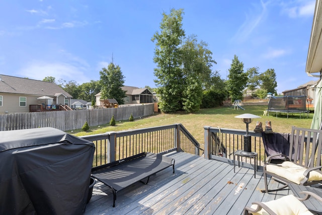 wooden deck with a trampoline, a lawn, and grilling area