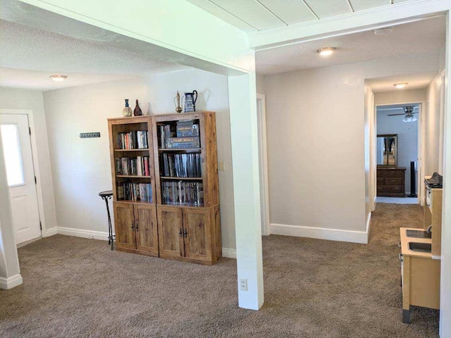 corridor featuring carpet floors, baseboards, and a textured ceiling