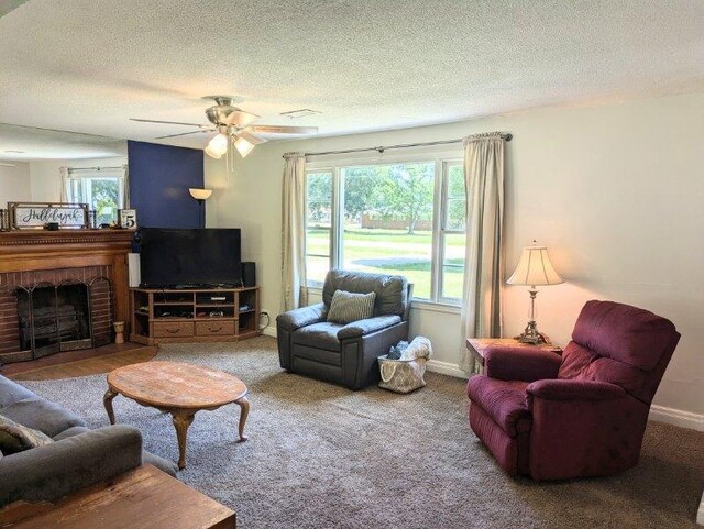 carpeted living room with a textured ceiling, ceiling fan, and a fireplace