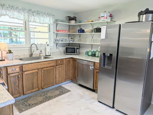 kitchen with light stone counters, a sink, brown cabinets, stainless steel appliances, and marble finish floor