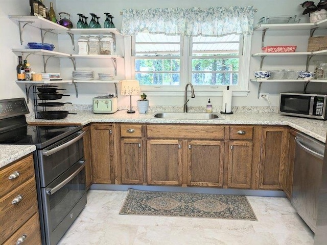 kitchen featuring marble finish floor, appliances with stainless steel finishes, a sink, open shelves, and brown cabinetry