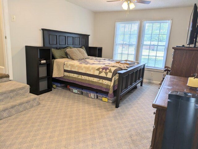 carpeted bedroom featuring ceiling fan and a textured ceiling