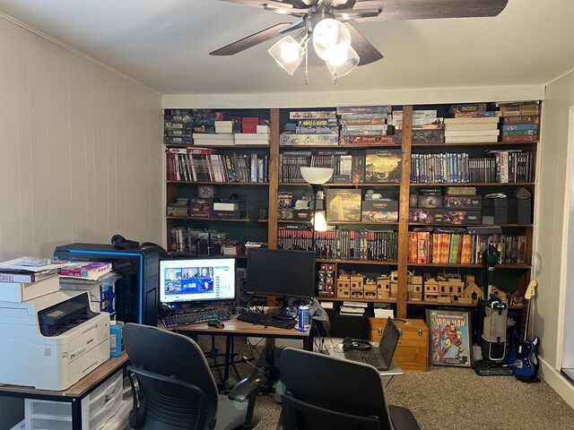 carpeted office space with ceiling fan, wooden walls, and crown molding