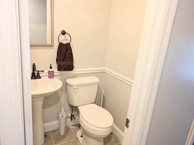 bathroom featuring toilet, tile patterned flooring, and wainscoting