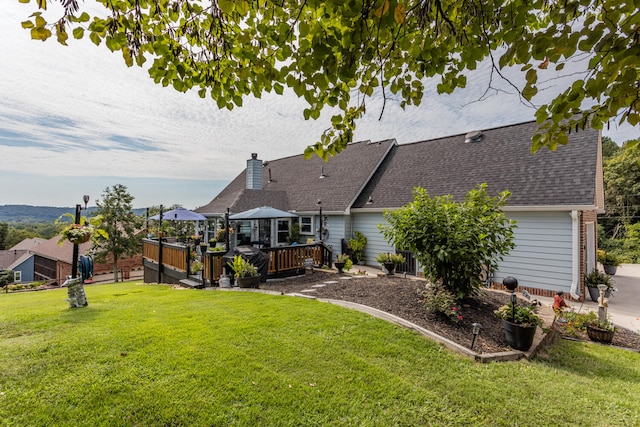 rear view of house with a wooden deck and a lawn