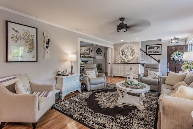 living room featuring ceiling fan, ornamental molding, and light hardwood / wood-style floors