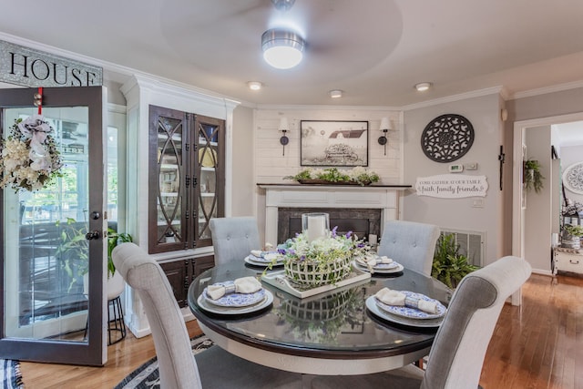 dining area with crown molding, a premium fireplace, and hardwood / wood-style floors