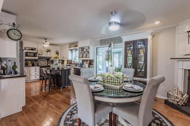 dining room with ceiling fan, ornamental molding, wood-type flooring, and a fireplace