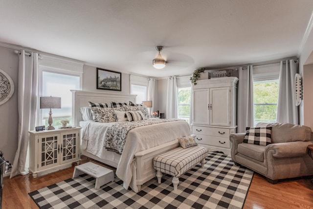 bedroom featuring multiple windows, hardwood / wood-style flooring, and ceiling fan