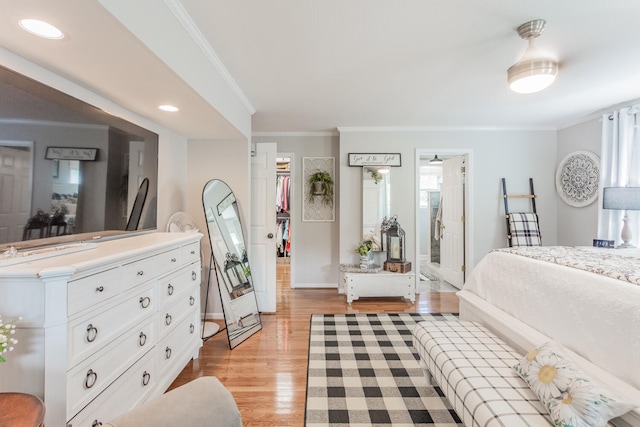 bedroom featuring crown molding, ensuite bath, light hardwood / wood-style flooring, a walk in closet, and a closet