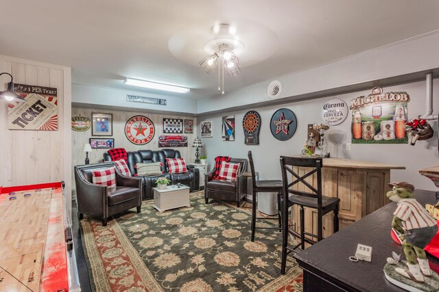 interior space with ceiling fan, wooden walls, and indoor bar