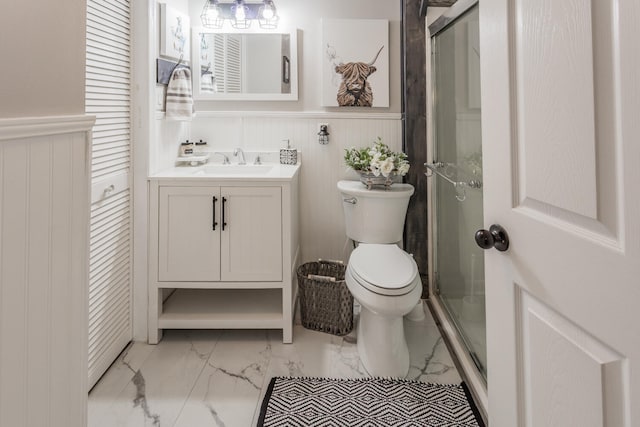 bathroom featuring a shower with door, vanity, and toilet