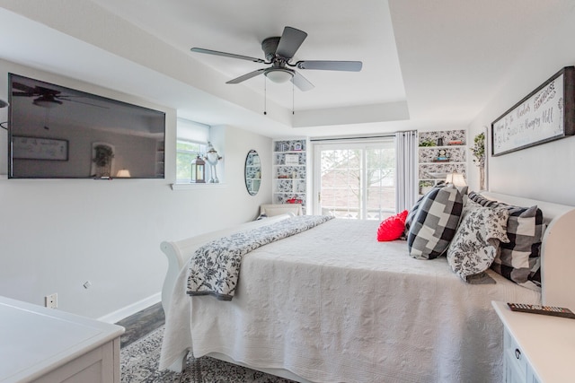 bedroom featuring ceiling fan, a tray ceiling, and multiple windows