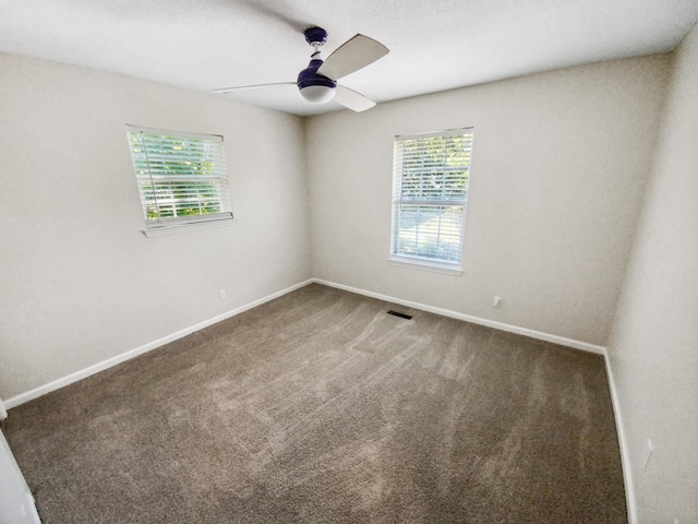 carpeted spare room featuring visible vents, baseboards, a healthy amount of sunlight, and ceiling fan