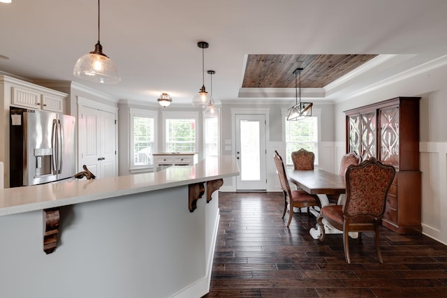 kitchen with pendant lighting, a kitchen bar, stainless steel fridge with ice dispenser, dark wood-type flooring, and a tray ceiling