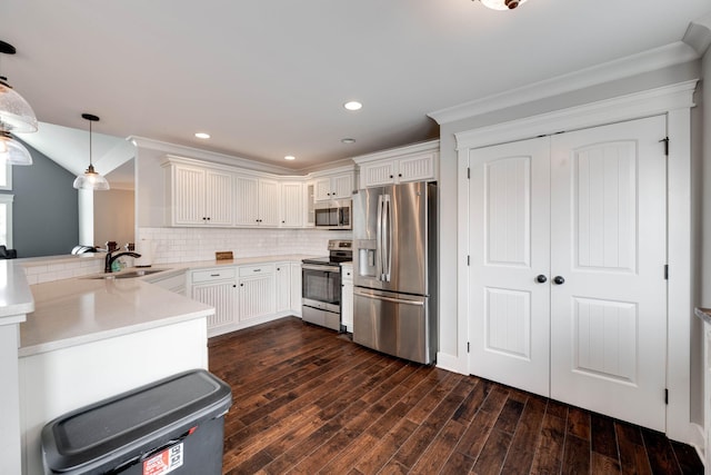 kitchen featuring stainless steel appliances, sink, dark hardwood / wood-style floors, kitchen peninsula, and pendant lighting