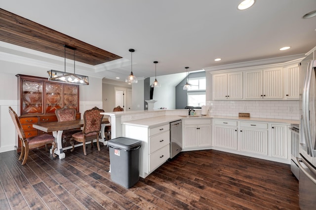 kitchen featuring appliances with stainless steel finishes, a raised ceiling, kitchen peninsula, dark wood-type flooring, and pendant lighting