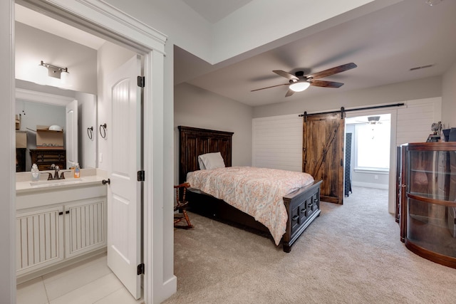 bedroom featuring a barn door, ceiling fan, sink, and light carpet