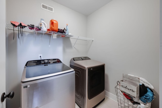 laundry area featuring washer and clothes dryer and light tile patterned flooring