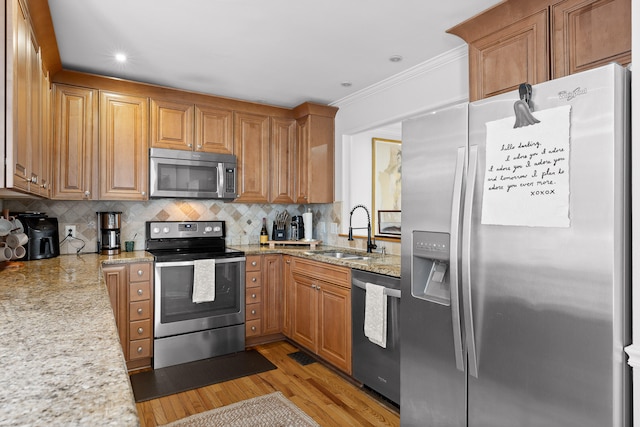 kitchen with crown molding, tasteful backsplash, light hardwood / wood-style flooring, stainless steel appliances, and sink