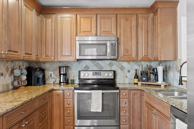 kitchen featuring stainless steel appliances, light stone counters, and backsplash