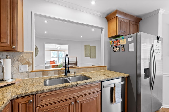 kitchen featuring crown molding, light stone counters, sink, and appliances with stainless steel finishes