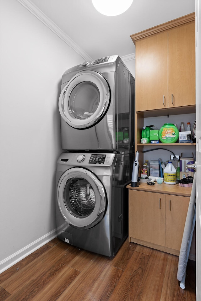 laundry area with crown molding, dark wood-type flooring, cabinets, and stacked washer and clothes dryer