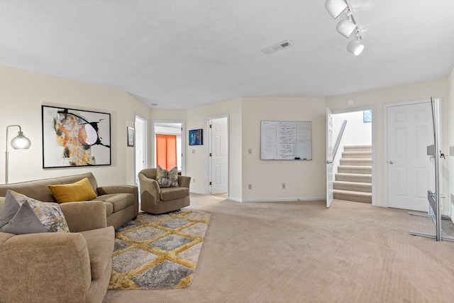 carpeted living room featuring rail lighting and a textured ceiling